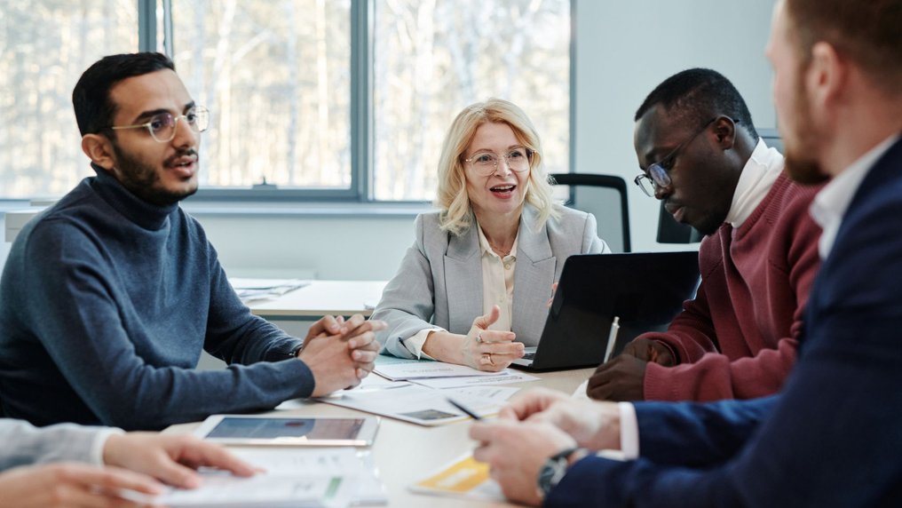 Une responsable s’adresse avec le sourire à ses collaborateurs lors d’un point d’équipe autour d’une table de réunion